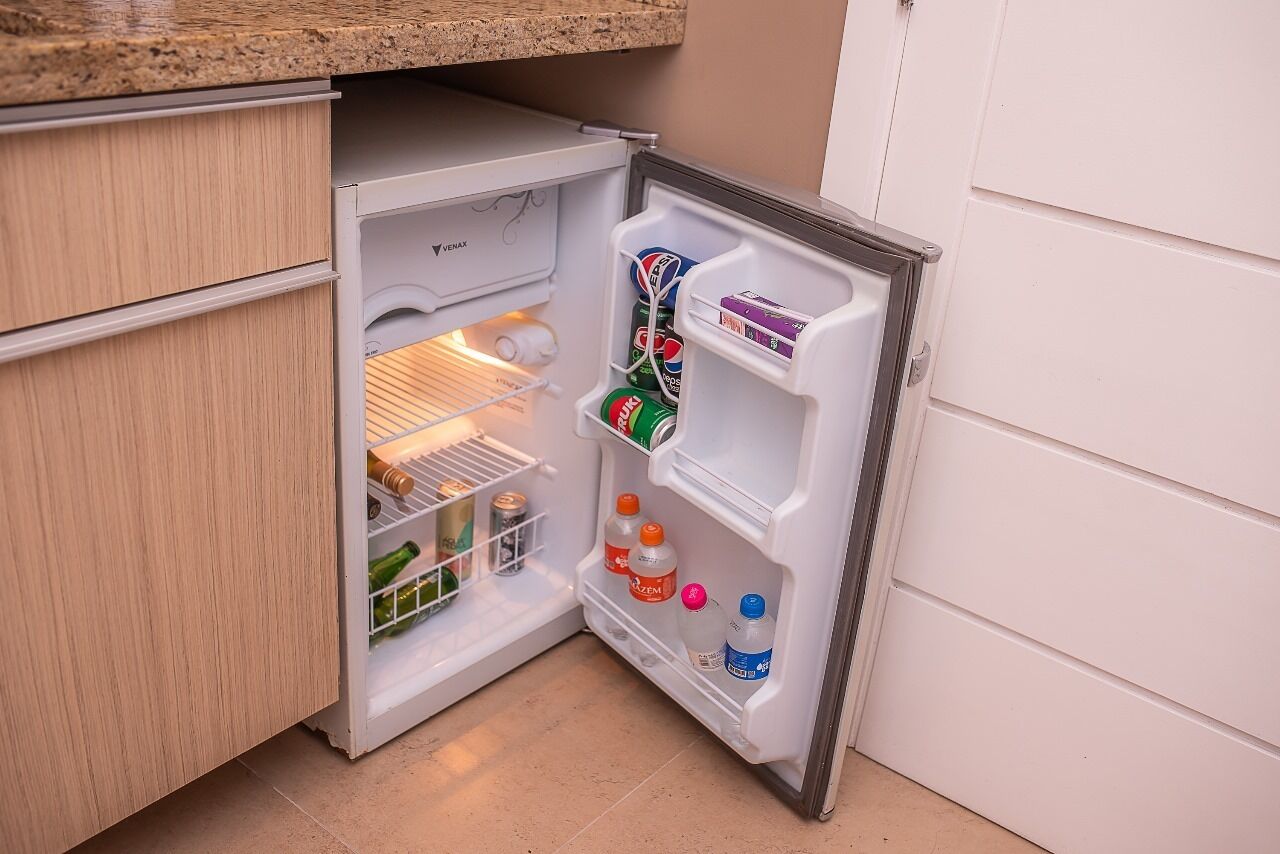 A compact refrigerator with multiple shelves, containing beverages and a few bottles.