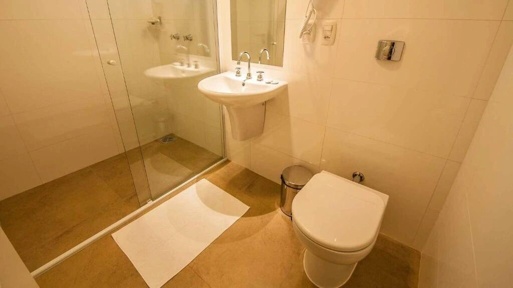 Een badkamer met een douchecabine van glas, een wastafel en een toilet.