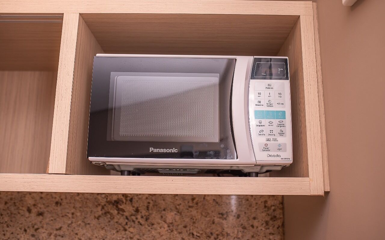 A microwave in a wooden drawer with a control panel displaying various settings.
