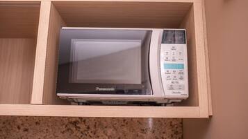 A microwave in a wooden drawer with a control panel displaying various settings.