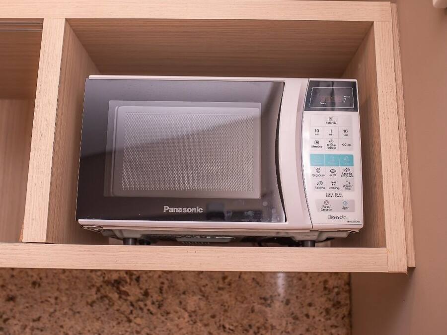A microwave in a wooden drawer with a control panel displaying various settings.