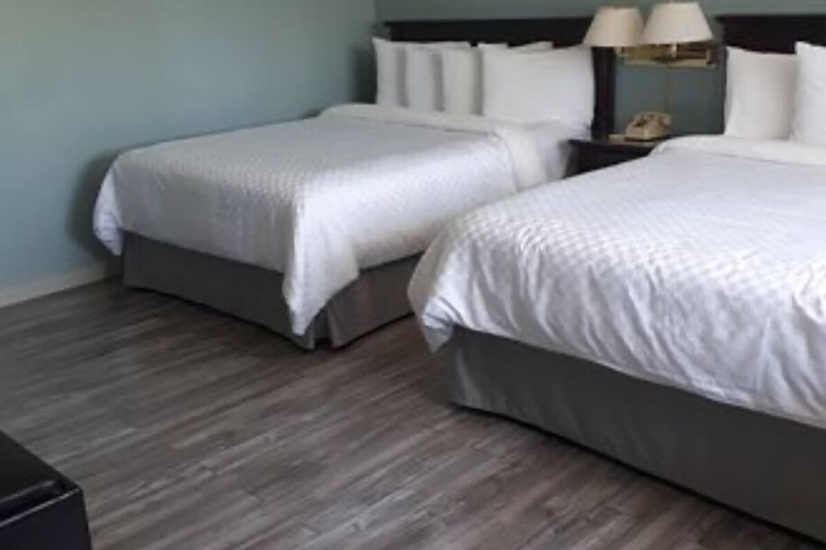 Une chambre d’hôtel avec deux lits, une table de chevet avec une lampe et un plancher en bois.