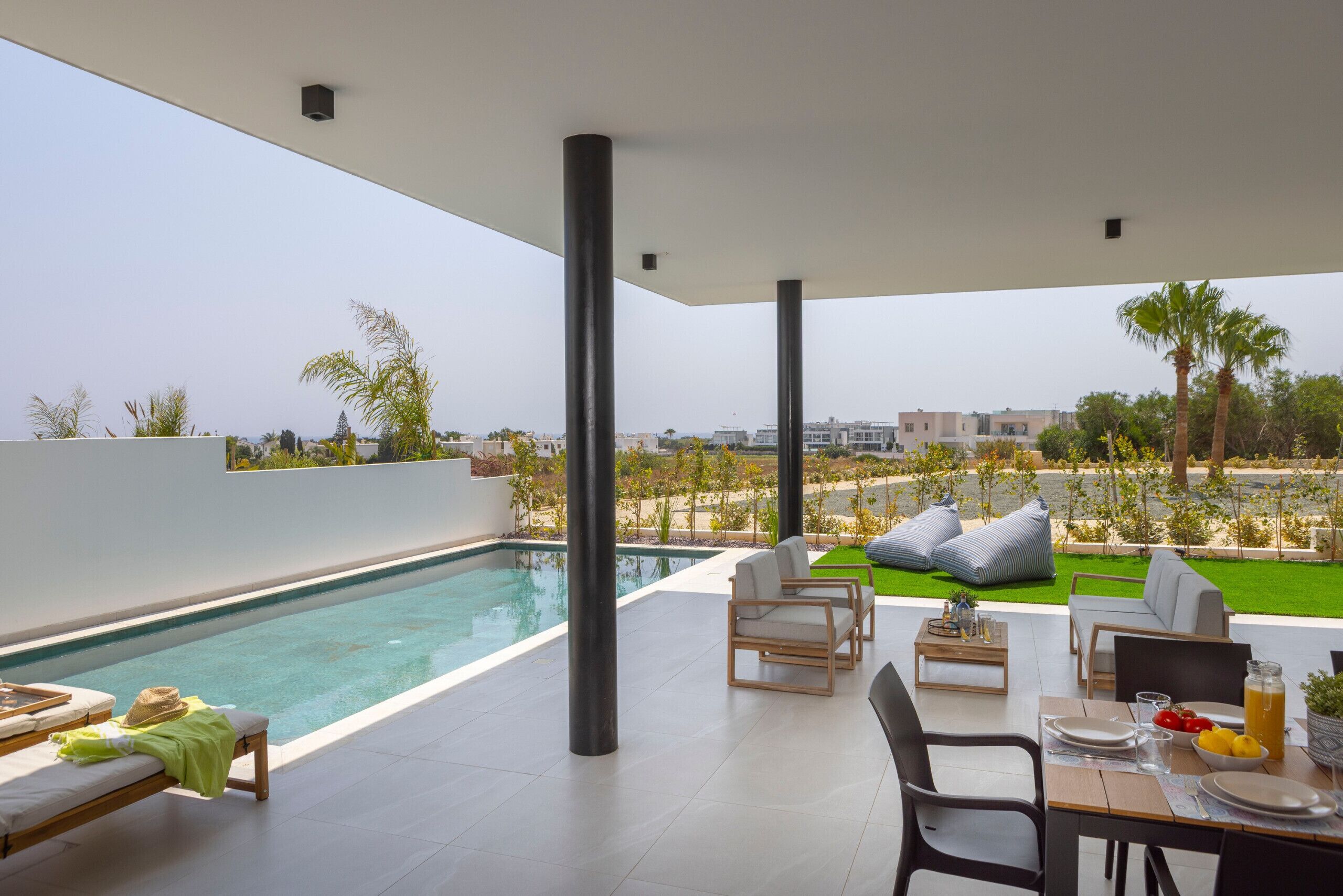 Ein moderner Poolbereich im Freien mit Liegestühlen, einem Esstisch und Blick auf die umliegende Landschaft.