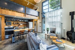 A modern kitchen with a dining area, a sofa, and a fireplace. - Sunny Open Home by Cafecito in Baca Railyard (Santa Fe)