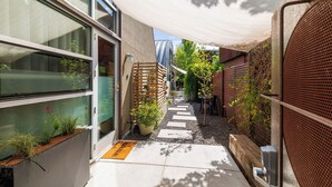 Un sendero estrecho que lleva a un edificio de diseño moderno, una valla de madera y una planta en maceta.