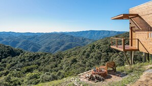 A wooden cabin with a deck overlooking a mountainous landscape. - Cabana c\Jacuzzi prox. de Florianópolis VST014 (Anitapolis)