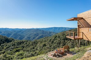 Eine Holzhütte mit einer Terrasse mit Blick auf eine gebirgige Landschaft.
