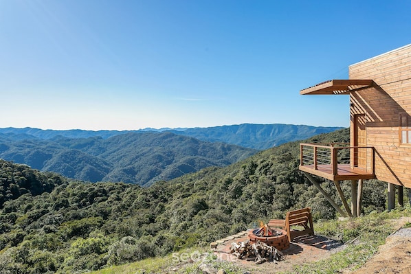 Una cabaña de madera con una terraza que da a un paisaje montañoso.