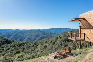 Una cabaña de madera con una terraza que da a un paisaje montañoso.