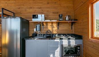 Una cocina compacta equipada con refrigerador, microondas, cafetera, hervidor y horno.