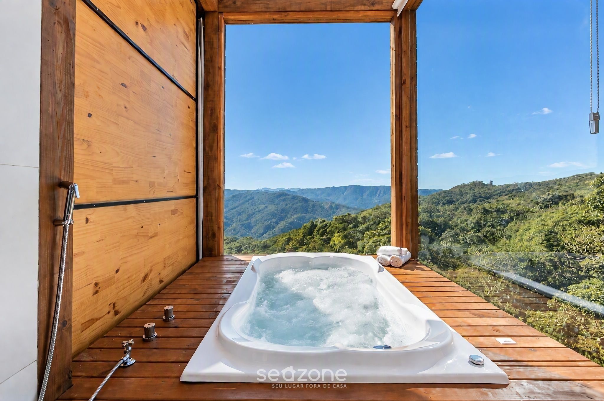 A wooden deck with a hot tub and a view of a mountainous landscape.