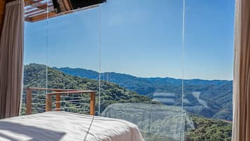 A room with a bed and a view of a mountainous landscape.