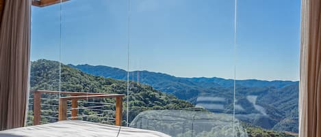 A room with a bed and a view of a mountainous landscape.