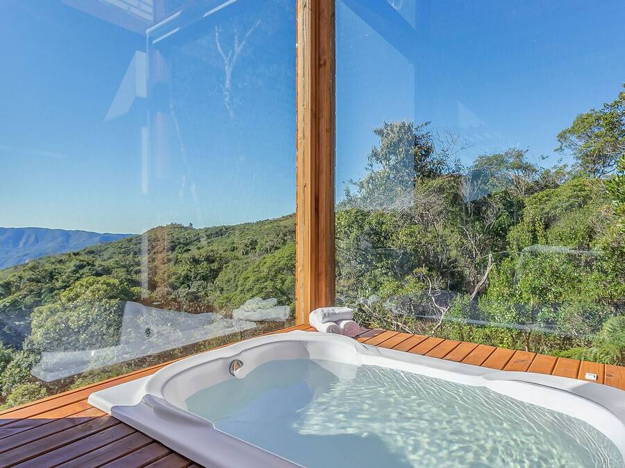 A hot tub on a wooden deck with a clear view of a mountainous landscape.
