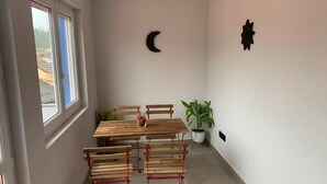A small dining area with a wooden table and benches, a potted plant, and wall decorations including a crescent moon and star.