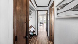 Un couloir au sol recouvert de parquet, une porte sur le côté gauche et un tableau encadré sur le mur de droite.