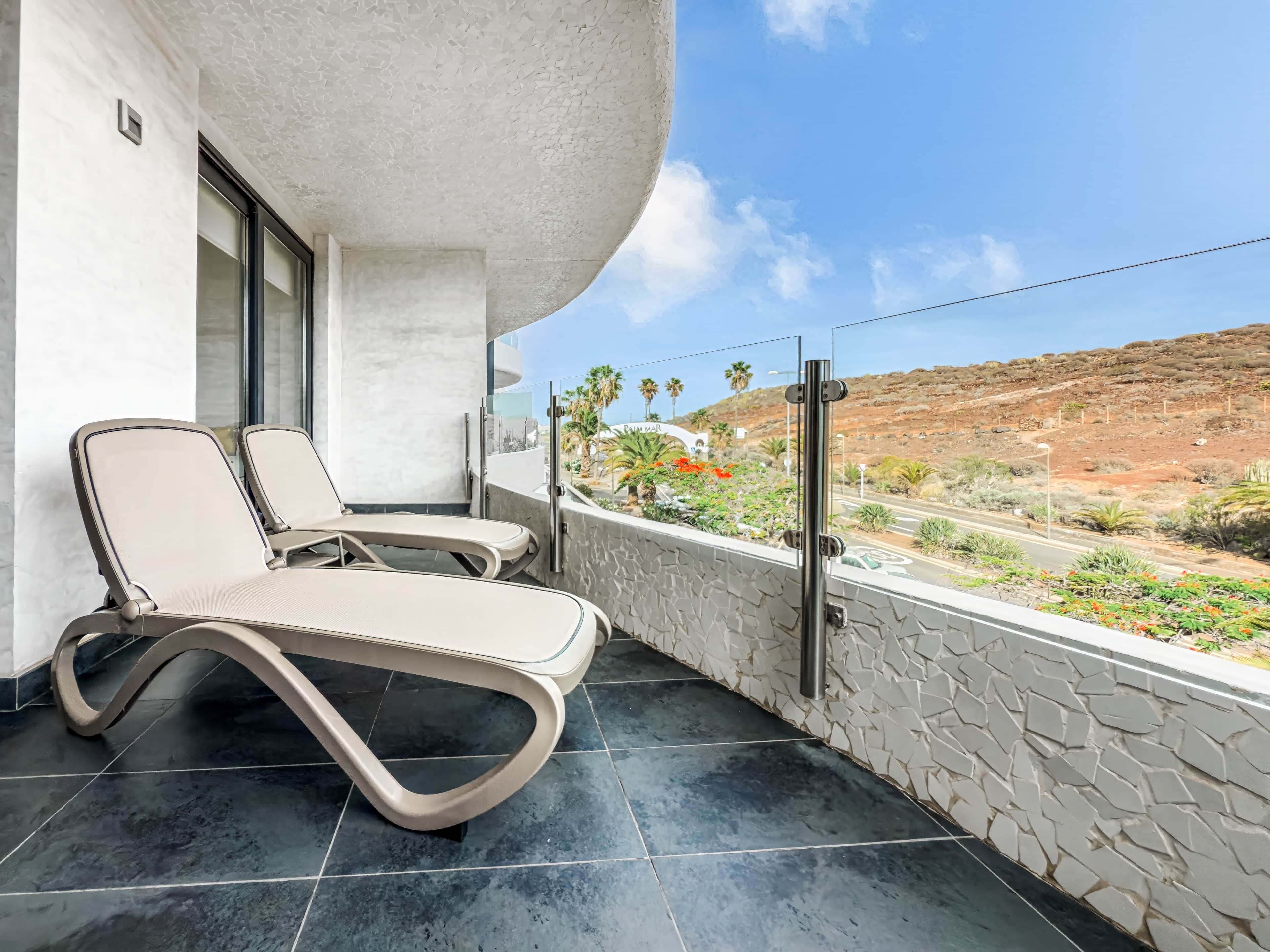 Un balcón con dos sillones, un muro de piedra y vistas al paisaje desértico.