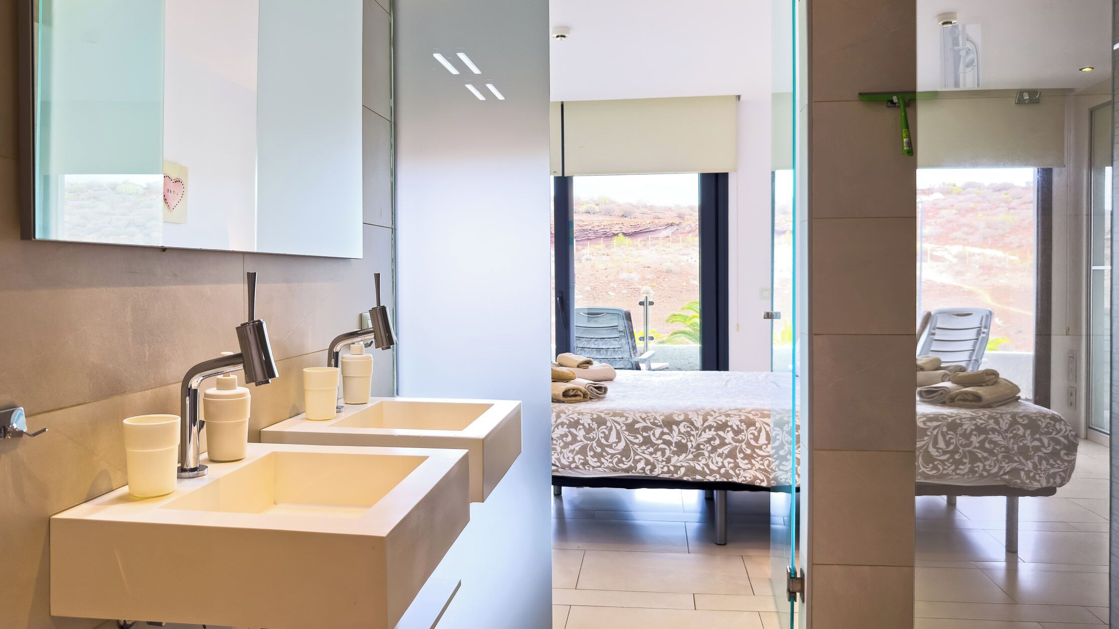 Een moderne badkamer met twee wasbakken, een spiegel en een raam.