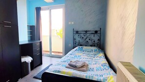 Ein Schlafzimmer mit Bett, Kleiderschrank, Heizkörper und Blick ins Freie.