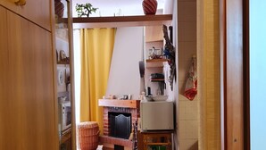 A kitchen with a tiled floor, wooden cabinets, a brick fireplace, and a yellow curtain. - Lodging in Artesina with Alpine view, ski-in/out, fireplace and sleeps 6 (Artesina)