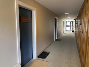 A hotel corridor with doors, a carpeted floor, and a wooden wall.