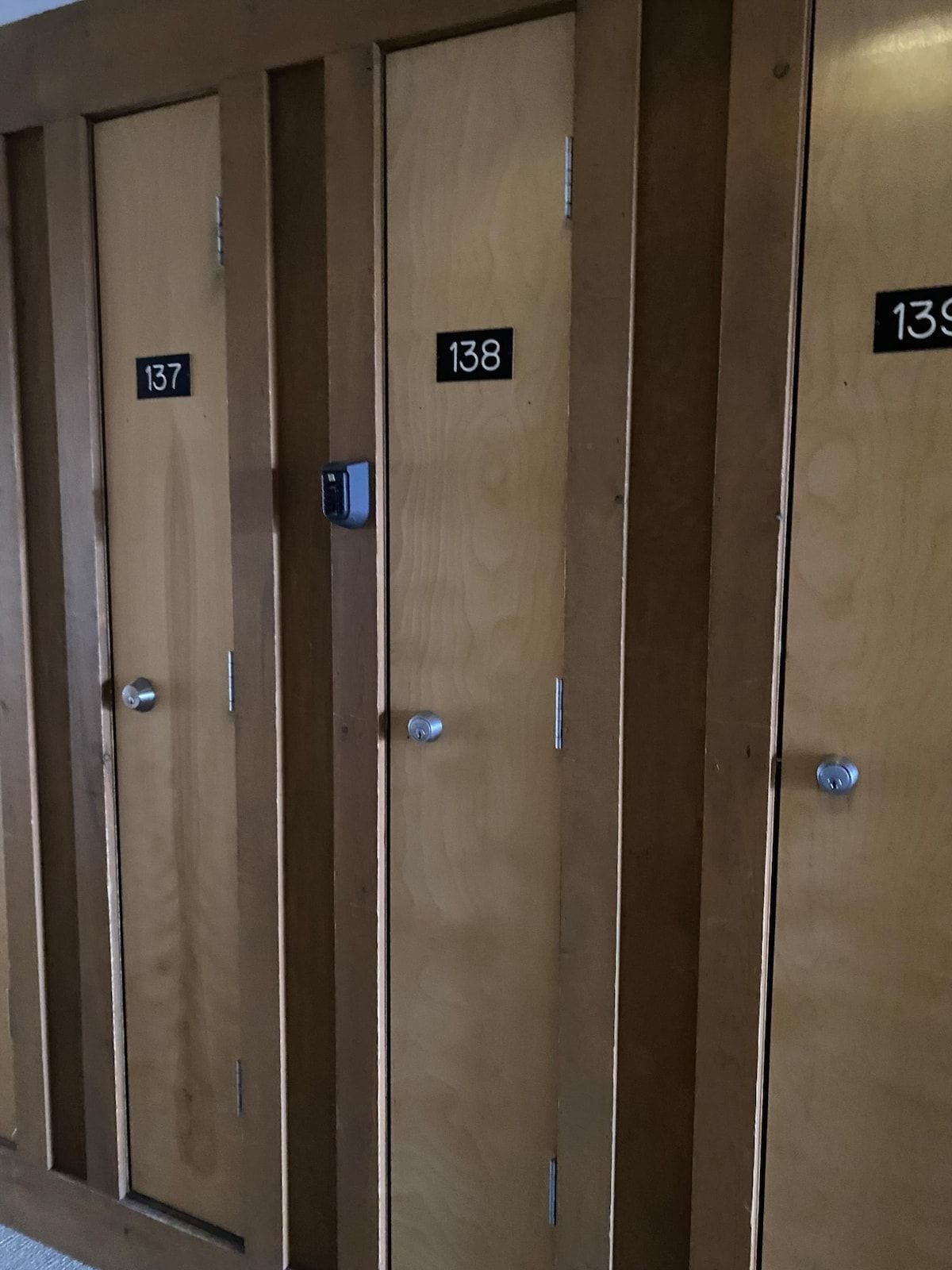 Fileira de portas de madeira com os números 137, 138 e 139, indicando um hotel ou alojamento similar.