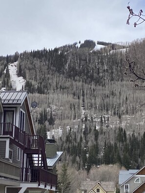 A residential area with a house featuring a balcony and a mountain backdrop.
