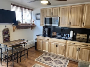 A kitchen with wooden cabinets, a black countertop, and a dining area with a table and chairs.
