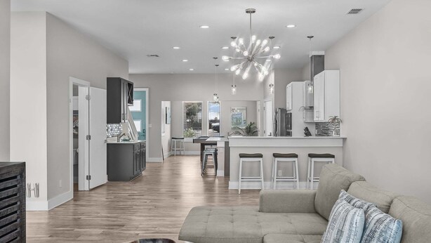 A modern living room with a sofa, a marble coffee table, and a kitchen area in the background. - Waterfront Condo With Rooftop + Pool + Boat Slips (Corpus Christi)