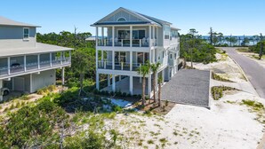 A multi-story beachfront house with a balcony, a covered porch, and a sandy driveway. - Little Sunshine (Cape San Blas)
