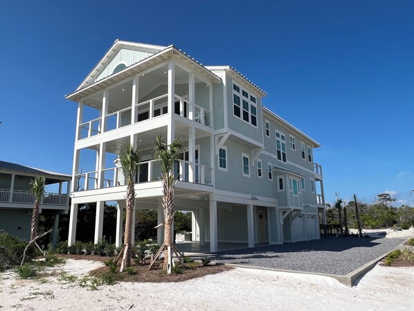 A two-story beachfront house with a covered balcony, a covered entryway, and a landscaped driveway. - Little Sunshine (Cape San Blas)