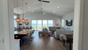 A spacious living area with a kitchen, dining area, and seating with a view of the ocean. - Little Sunshine (Cape San Blas)