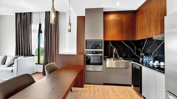 A modern kitchen with stainless steel appliances, a wooden dining table, and a view of the outdoors.