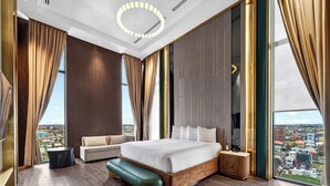 Een moderne hotelkamer met een groot bed, een bank, een zitje en uitzicht op de stad.
