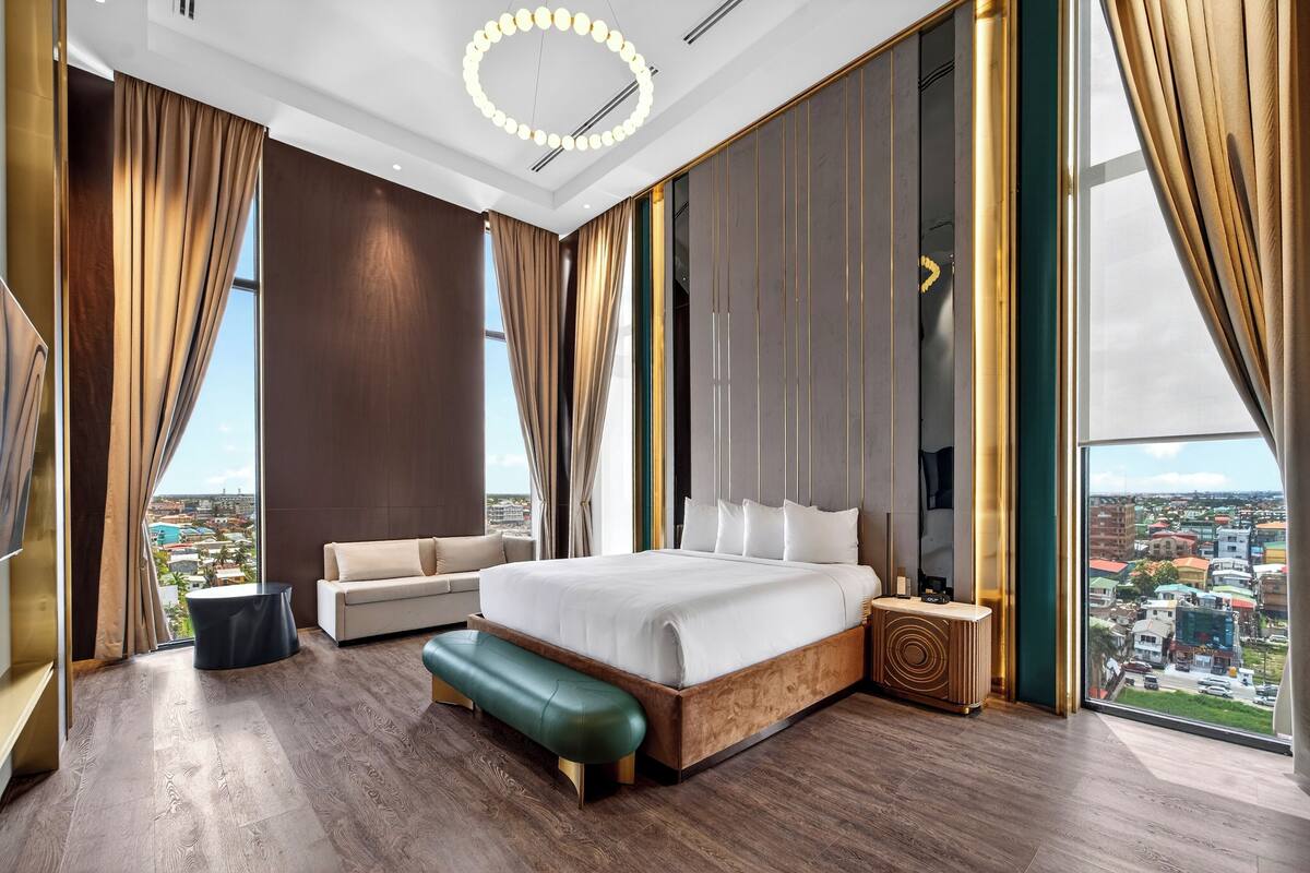 Une chambre d’hôtel moderne dotée d’un grand lit, d’un canapé, d’une banquette et offrant une vue sur la ville.