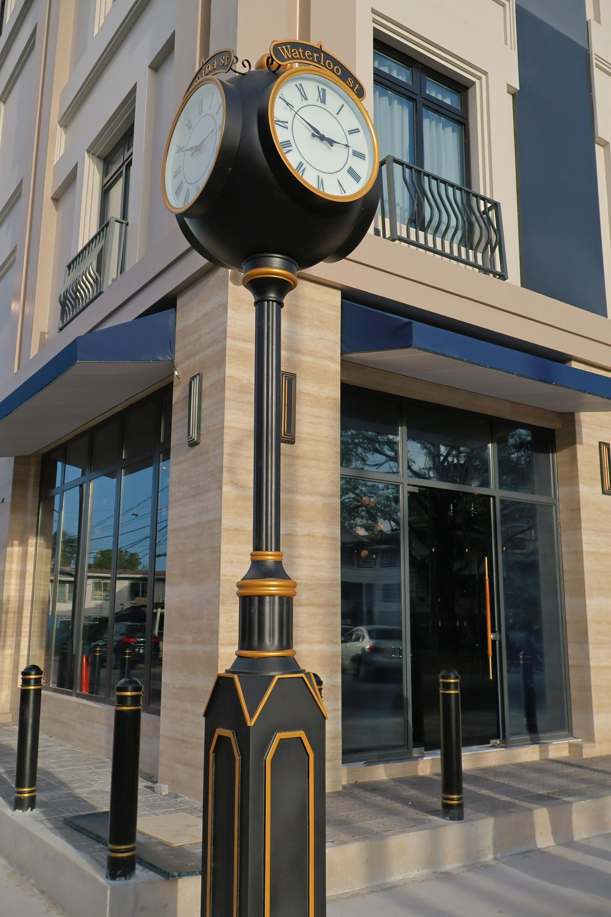 A clock with "Waterloo St" on it, mounted on a pole with decorative elements.
