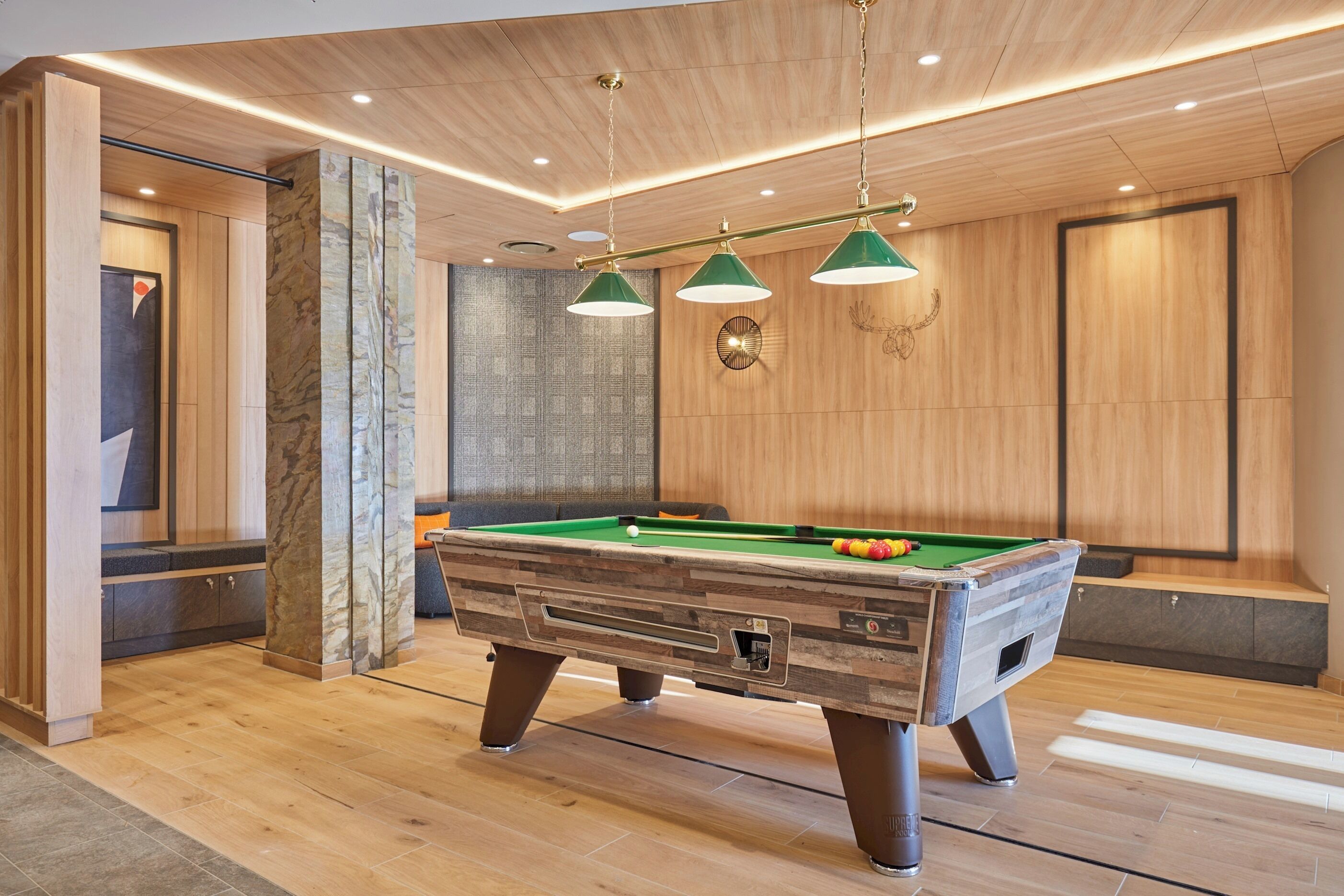 Una mesa de billar en una habitación moderna con suelo y pared de madera.