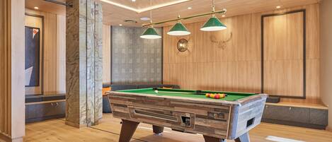 Una mesa de billar en una habitación moderna con suelo y pared de madera.