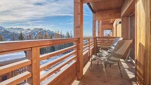 Une terrasse en bois offrant une vue sur des montagnes enneigées et un ciel dégagé.