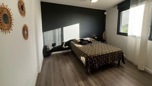 A bedroom with a bed, a ceiling fan, and a window with curtains.