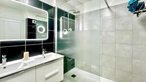 A modern bathroom with a white vanity, a large mirror, a bathtub, and a shower.