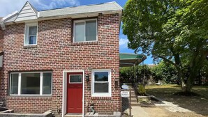 A two-story brick building with a red door and two windows on the ground floor. - Kingdom luxury (Darby)