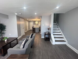 A modern interior with a dining area, sofa, staircase, and kitchen.