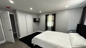 A bedroom with a bed, a TV mounted on the wall, a wardrobe, and a window with curtains. - Kingdom luxury (Darby)