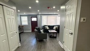 A spacious living area with a grey sofa set, a coffee table, and a dining table. - Kingdom luxury (Darby)