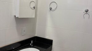 A bathroom with a white sink, black countertop, and white tiled walls. - Hotel Jatobás Sinop (Sinop)
