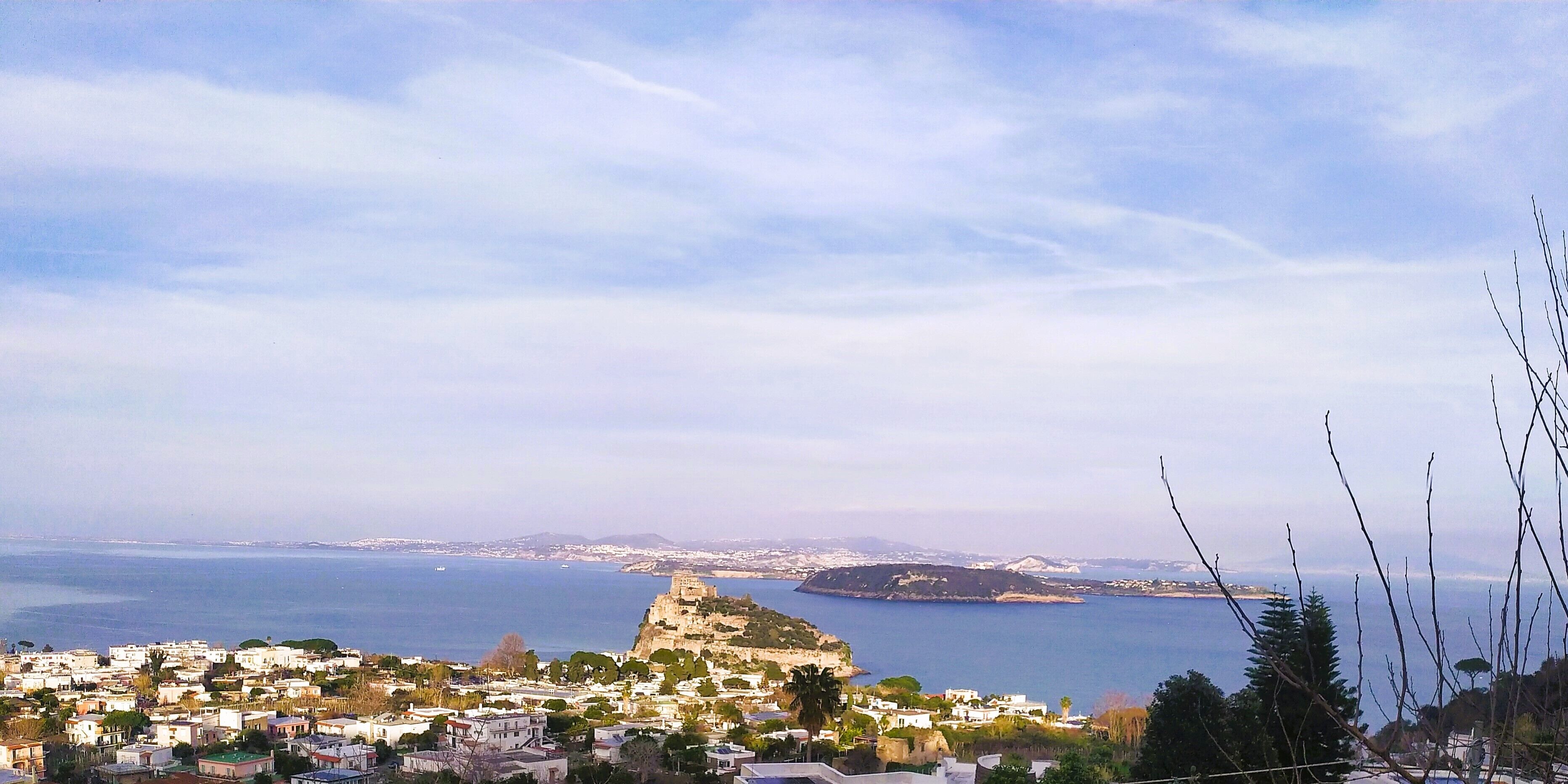 A coastal town with a prominent castle on a hill, surrounded by residential buildings and a view of the sea.