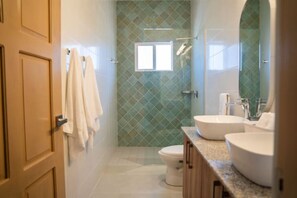 Une salle de bain avec deux lavabos, des toilettes et un espace douche.