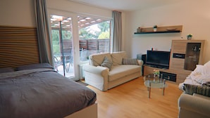A modern living room with a sofa, a glass coffee table, a TV, and a wooden cabinet. - Apartment Braunlage Near Wurmberg Ski Area (Braunlage)