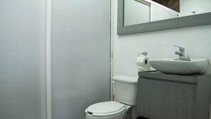 A bathroom with a toilet, sink, and mirror.
